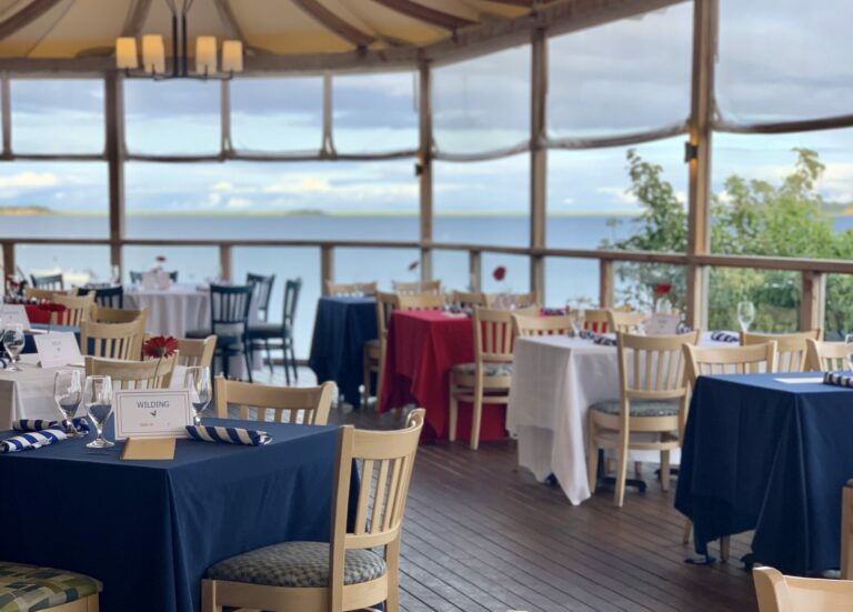 A scenic restaurant with tables set for dining, overlooking a view of the ocean.