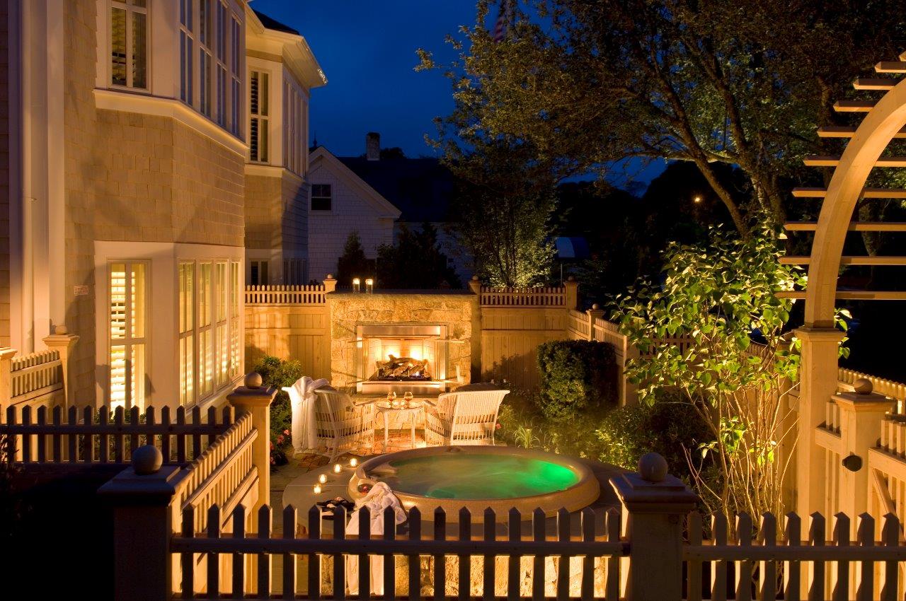 Outdoor jacuzzi and fireplace with chairs nearby at Wequassett Resort
