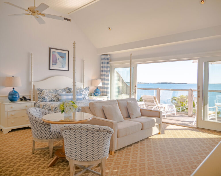 Hotel cottage room with a white couch and bed overlooking the Cape Cod ocean.